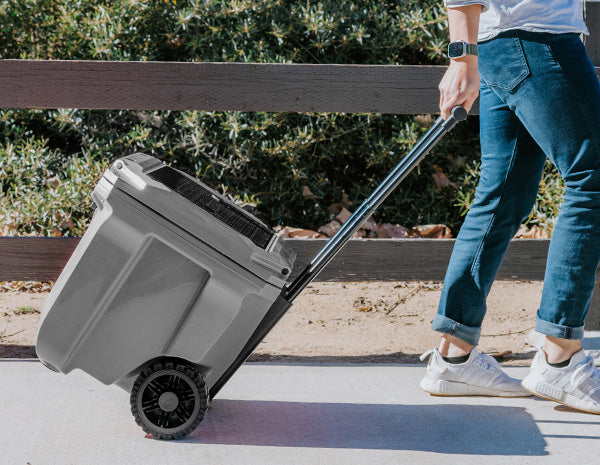 Image of a person rolling a BrüTank cooler outside.