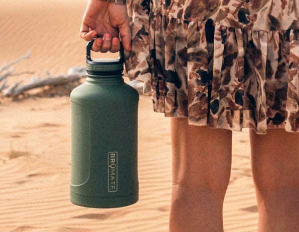 Image of someone holding a Growl'r outside in a desert setting.