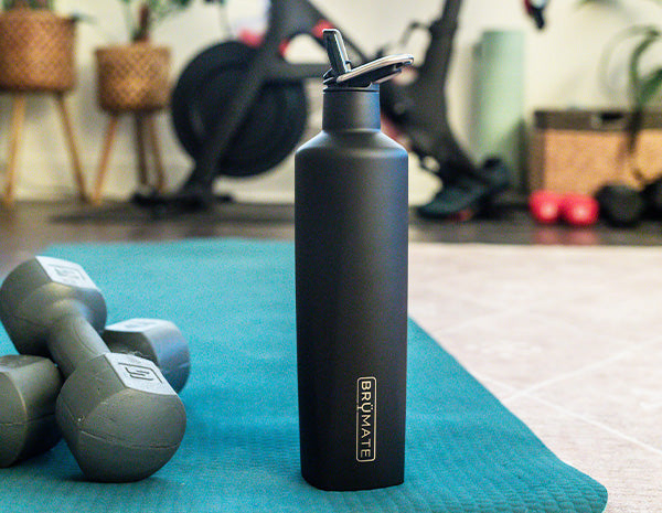 Image of a black ReHydration Bottle sitting on a mat in the gym.