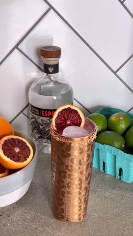 tumbler with limes and tequila next to it.